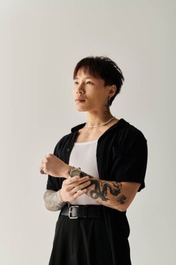 Kendine güvenen genç adam modern, minimalist bir mekanda dövmelerle şık görünümünü sergiliyor..