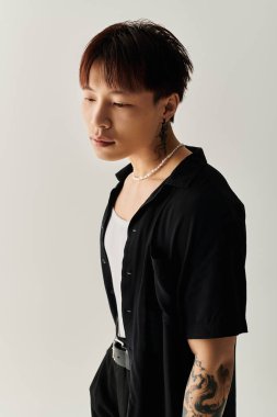 Genç yakışıklı bir Asyalı, kendine has tarzını doğal ışıkla minimalist bir ortamda sergiliyor..