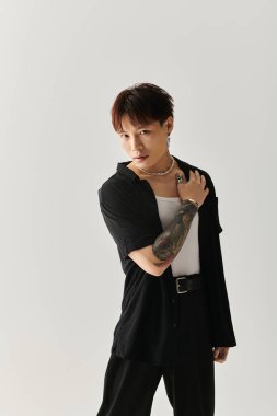 Kendine güvenen genç adam, minimalist bir stüdyoda modern stil ve çarpıcı giysiler sergiliyor..