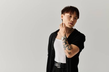 Genç adam şık bir stüdyoda kendine güvenen bir şekilde poz verirken şık kıyafetlerini sergiliyor..