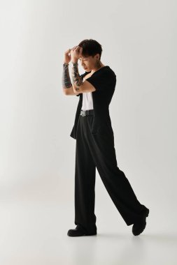 Genç, yakışıklı bir Asyalı moda anlayışını minimalist bir stüdyo ortamında sergiliyor..