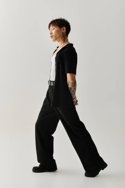 Genç, yakışıklı Asyalı bir adam şık, minimalist stüdyo alanında kendine güvenerek yürüyor..