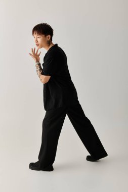 Yakışıklı Asyalı genç bir adam minimalist bir stüdyoda büyüleyici bir pozla tarzını sergiliyor..