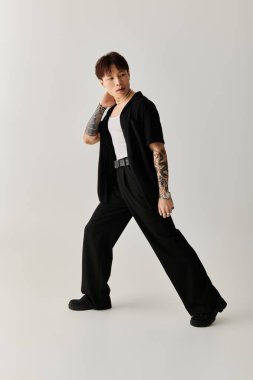 Şık, genç Asyalı bir adam minimalist bir stüdyoda güven içinde poz veriyor..