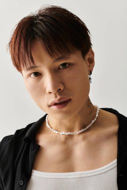 Genç Asyalı bir adam şık bir stüdyoda şık bir kıyafetle poz veriyor..