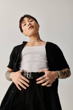 Genç, şık Asyalı bir adam dingin bir ortamda güvenle duruyor..