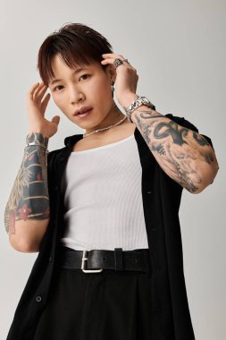 Kendine güveni olan genç bir adam şık bir elbise ve sanatsal bir ortamda dövmeler sergiliyor..