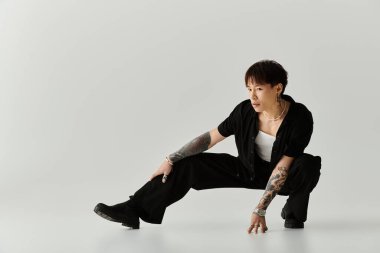 Genç yakışıklı Asyalı adam modern stüdyo ortamında benzersiz pozlarla moda sergiliyor..