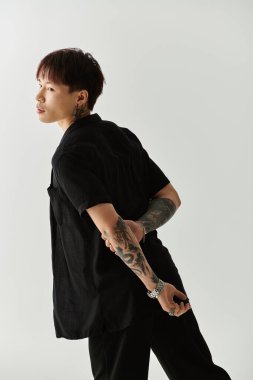 Şık bir genç adam şık bir elbiseyle hafif bir arkaplanda rahatça poz verir..