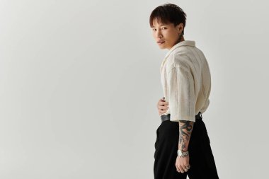 Modaya uygun genç Asyalı adam stilini minimalist bir ortamda sergiliyor..