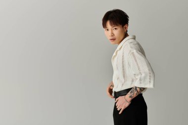 Kendine güvenen genç adam benzersiz stilini ve dövmelerini modern ve minimalist bir ortamda sergiliyor..