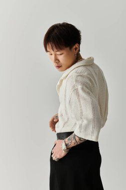 Şık saç stili olan genç bir Asyalı şık ve dengeli bir şekilde moda anlayışını sergiliyor..