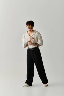 Genç ve yakışıklı bir adam moda anlayışını minimalist bir mekanda moda kıyafetleriyle sergiliyor..