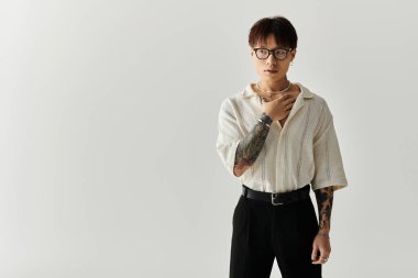Genç, yakışıklı Asyalı bir adam minimal bir stüdyoda kendi tarzını sergileyerek poz veriyor..