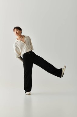 Genç yakışıklı bir Asyalı parlak bir stüdyoda kendine güvenen bir şekilde poz verirken şık kıyafetler sergiliyor..