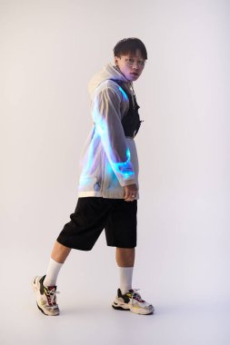 Modaya uygun genç Asyalı bir adam, çağdaş kıyafetler içinde kendinden emin bir şekilde poz verir, tarz ve cazibe yayar..