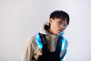 Genç, yakışıklı Asyalı bir adam şık görünümünü minimalist bir ortamda parlayan aksanıyla sergiliyor..