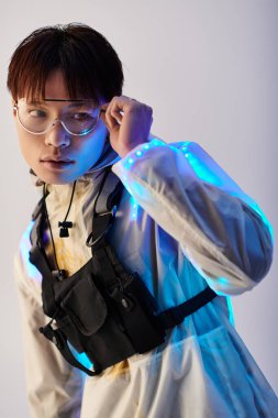 Modaya uygun genç Asyalı adam gözlüklerini ayarlıyor, şık bir ortamda parlıyor..