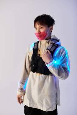 Şık bir Asyalı genç adam kendine güvenerek LED aksanlı bir kıyafet sergiliyor..