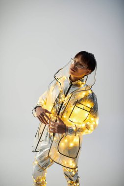 Parlak ışıklar şık bir Asyalı adamın etrafında parıldıyor. Parlak ceketli, hareketli bir hava yaratıyor..