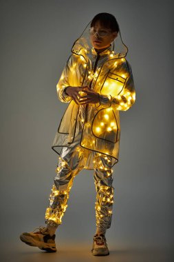 Şık, genç Asyalı bir adam pırıl pırıl, parıldayan bir kıyafetin içinde duruyor..