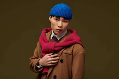 Şık bir iç mekanda, genç bir adam stilini mavi bir bere ve kırmızı bir eşarpla geliştirir..