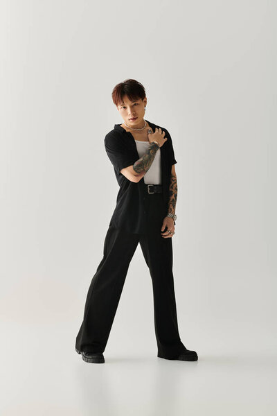 Молодой красивый азиатский мужчина элегантно стоит в повседневной, но стильной одежде, источая уверенность.