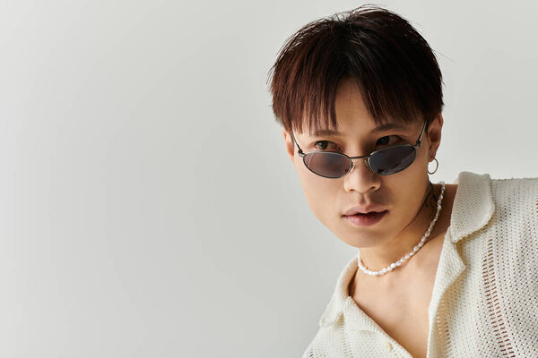 A young Asian man embodies urban chic with his stylish outfit and accessories.