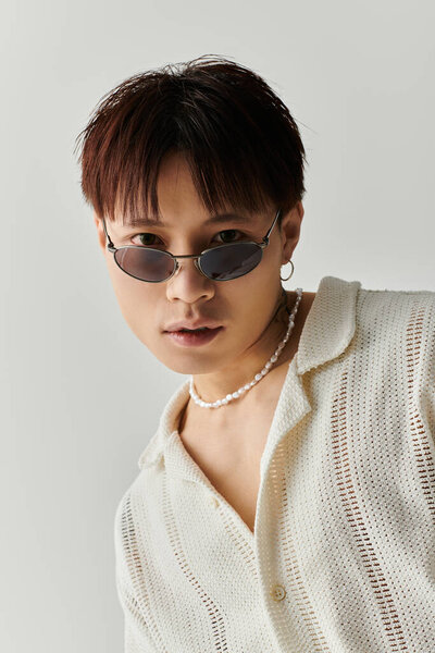 A young, stylish Asian man poses confidently with unique accessories.