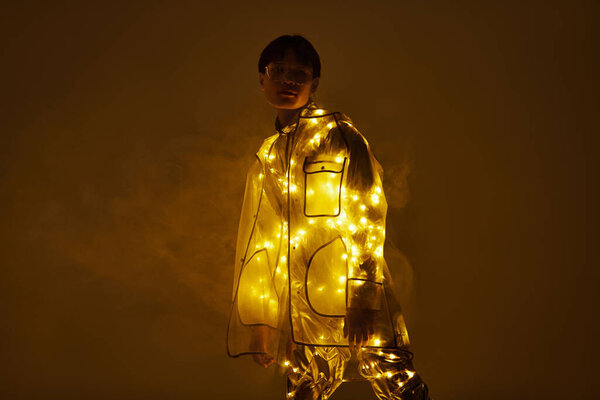 Молодой красивый азиат уверенно стоит, одетый в блестящий костюм.