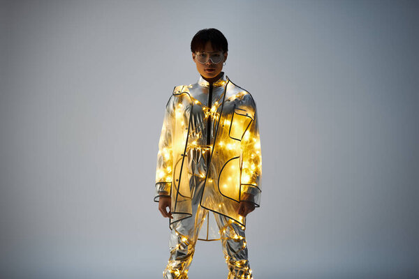 Молодой, стильный азиат уверенно стоит, светящийся мерцающими огнями в творческой атмосфере.