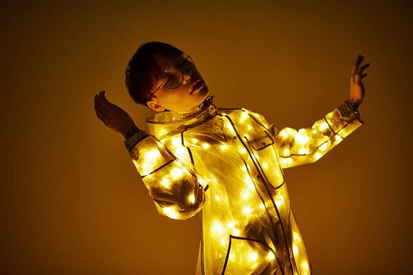 Энергичный молодой человек изящно танцует, украшенный светящимся пальто, выражая радость и стиль.