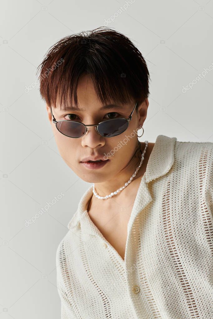 A young, stylish Asian man poses confidently with unique accessories.