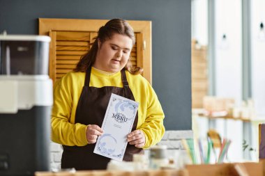 Büyüleyici bir kafede Down sendromlu genç bir kadın menüyü inceleyip kendine güveni yayıyor..