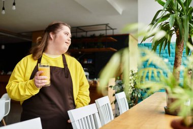 Down sendromlu kendine güvenen genç bir kadın bir kafede içki içip etrafa bakıyor..