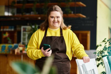Down sendromlu genç bir kadın telefonunu bir kafede güvenle kullanıyor ve havanın tadını çıkarıyor..
