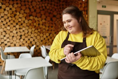 Neşeli bir kafede, Down sendromlu genç bir kadın çalışırken gülümsüyor..