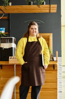 Down sendromlu genç bir kadın yoğun bir kafede kendine güvenerek hizmet ediyor. Parlak, günlük kıyafetler giyiyor..