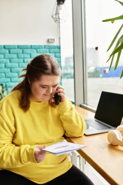 Down sendromlu genç bir kadın bir kafede dinleniyor ve bir belgeyi okuyor..