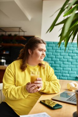 Parlak bir kafede Down sendromlu genç bir kadın çalışırken kendine güvenerek içkisini yudumluyor..