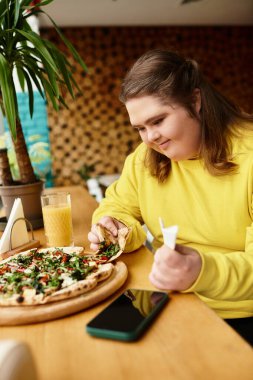 Down sendromlu genç bir kadın canlı bir kafede pizza ve içkiden hoşlanır..