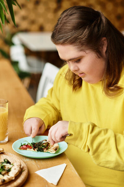 Молодая женщина с синдромом Дауна наслаждается едой, демонстрируя радость и уверенность в кафе.
