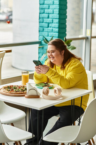 В оживленном кафе молодая женщина с синдромом Дауна радостно улыбается друзьям, разговаривая по телефону.