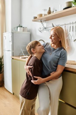 Bir anne, şık mutfağında kaliteli zaman geçirirken oğlunu sıcak bir şekilde kucaklar..
