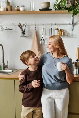 Kadın ve çocuk, modern aile dinamiklerini somutlaştıran şık bir mutfakta sevgi dolu bir etkileşimden hoşlanırlar..