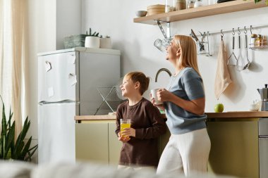 Bir kadın ve küçük oğlu, şık mutfaklarında içkileriyle neşeli bir anı paylaşıyorlar..