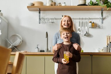 Bir anne ve oğul, içecekler ve kahkahalar eşliğinde şık mutfaklarında neşeyle kaynaşırlar..