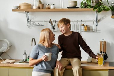 Bir anne sıcak, modern bir mutfakta içkisini yudumlarken oğluyla neşeli bir sohbet eder..