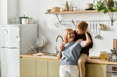 Bir anne, şık mutfağında oyun sırasında oğluyla keyifli bir anı paylaşır..
