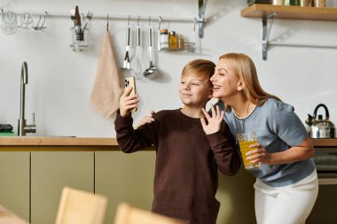 Bir anne ve oğul güneşli mutfaklarında selfie çekerken birlikte gülerler..